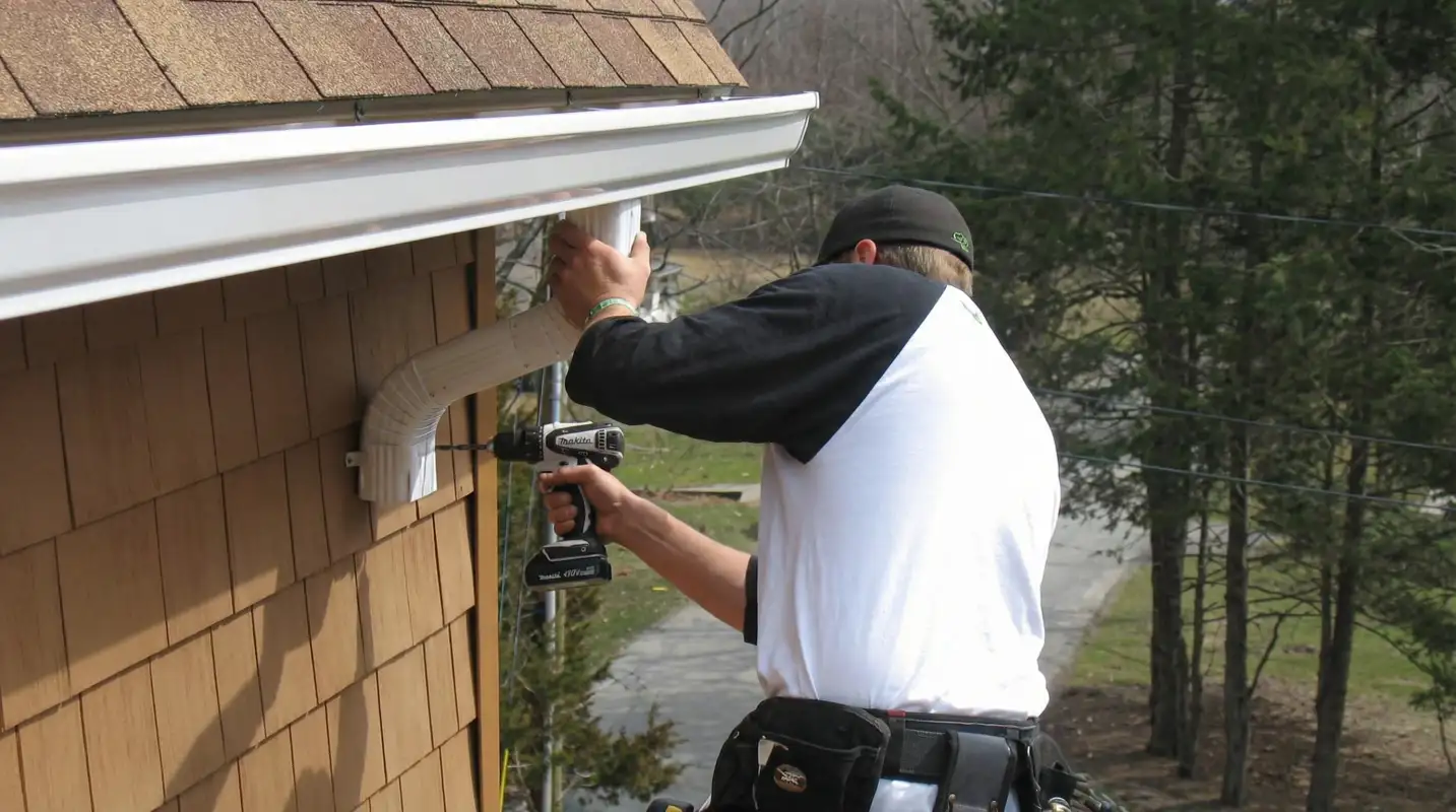 Professional contractor installing tan vinyl siding panels on a residential home exterior in Huntsville, AL